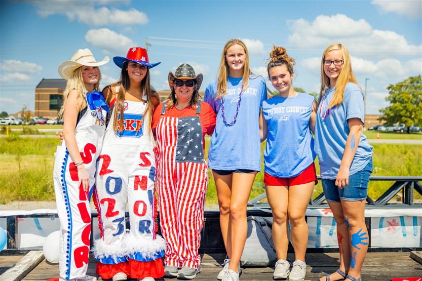 Five students and a teacher smile on a float
